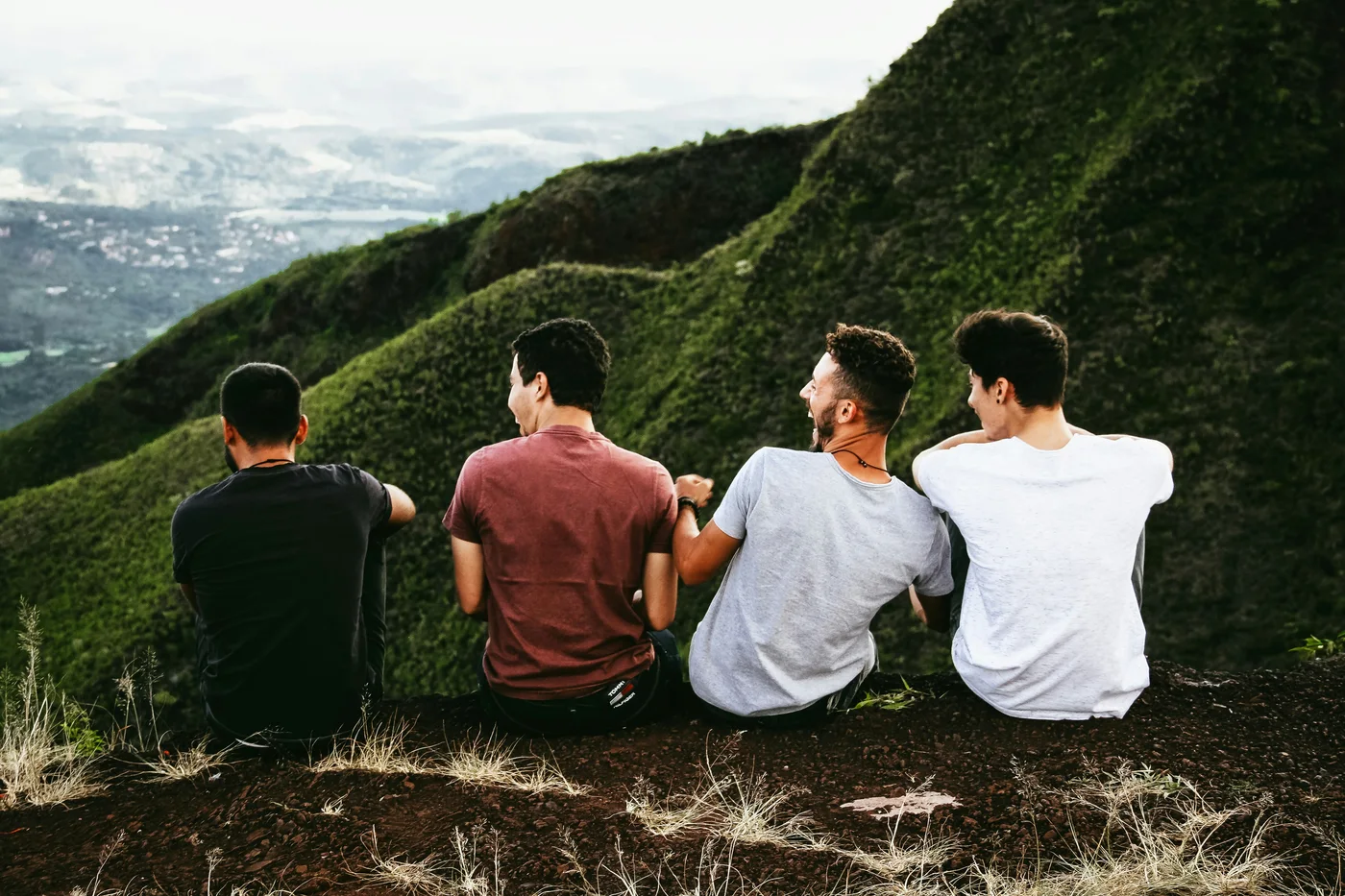 Four friends sitting together overlooking a green mountain vista